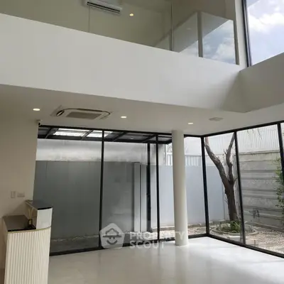 Spacious modern living room with high ceilings and large windows offering natural light.