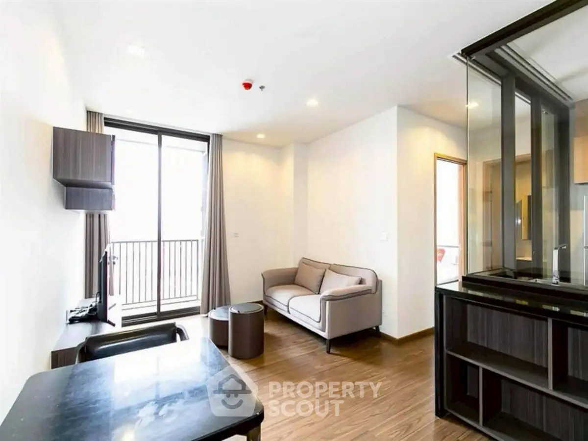 Modern living room with sleek furniture and balcony access in a bright apartment.