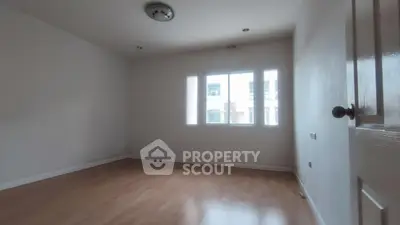 Spacious empty room with wooden flooring and large windows, ideal for customization.