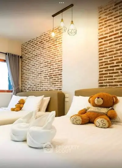 Charming bedroom with brick accent wall and cozy teddy bear decor.