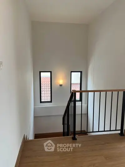 Elegant staircase with wooden flooring and modern railing in a bright home interior.