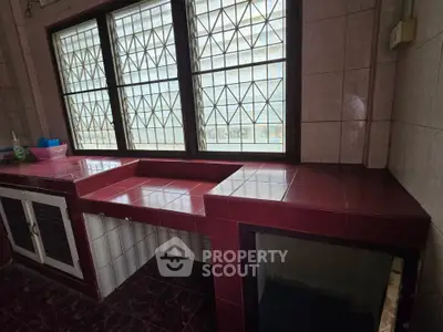 Spacious kitchen with tiled countertops and large window for natural light.