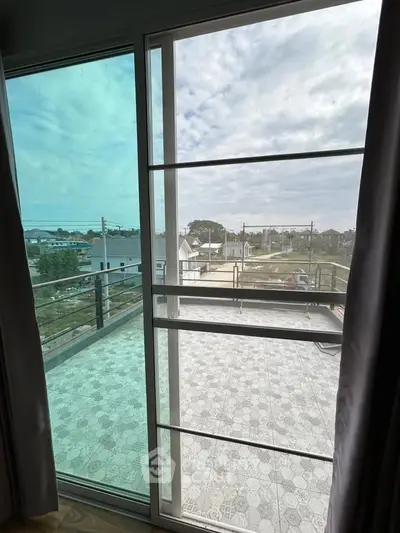 Spacious balcony with scenic view and modern railing in a residential area.