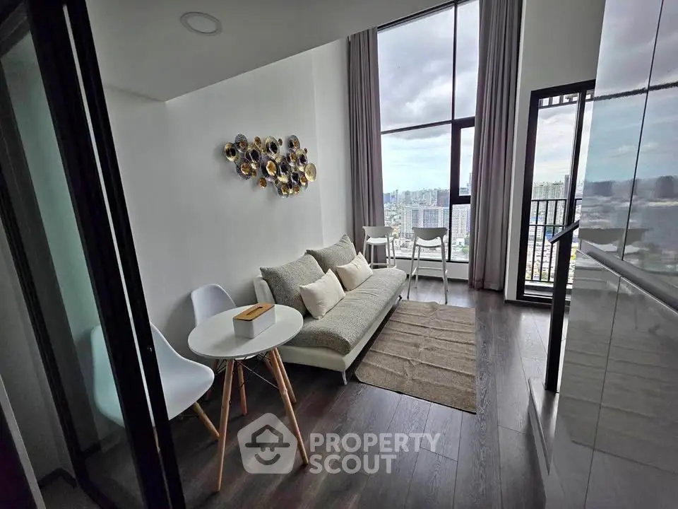 Modern living room with high ceiling and city view, featuring stylish decor and floor-to-ceiling windows.