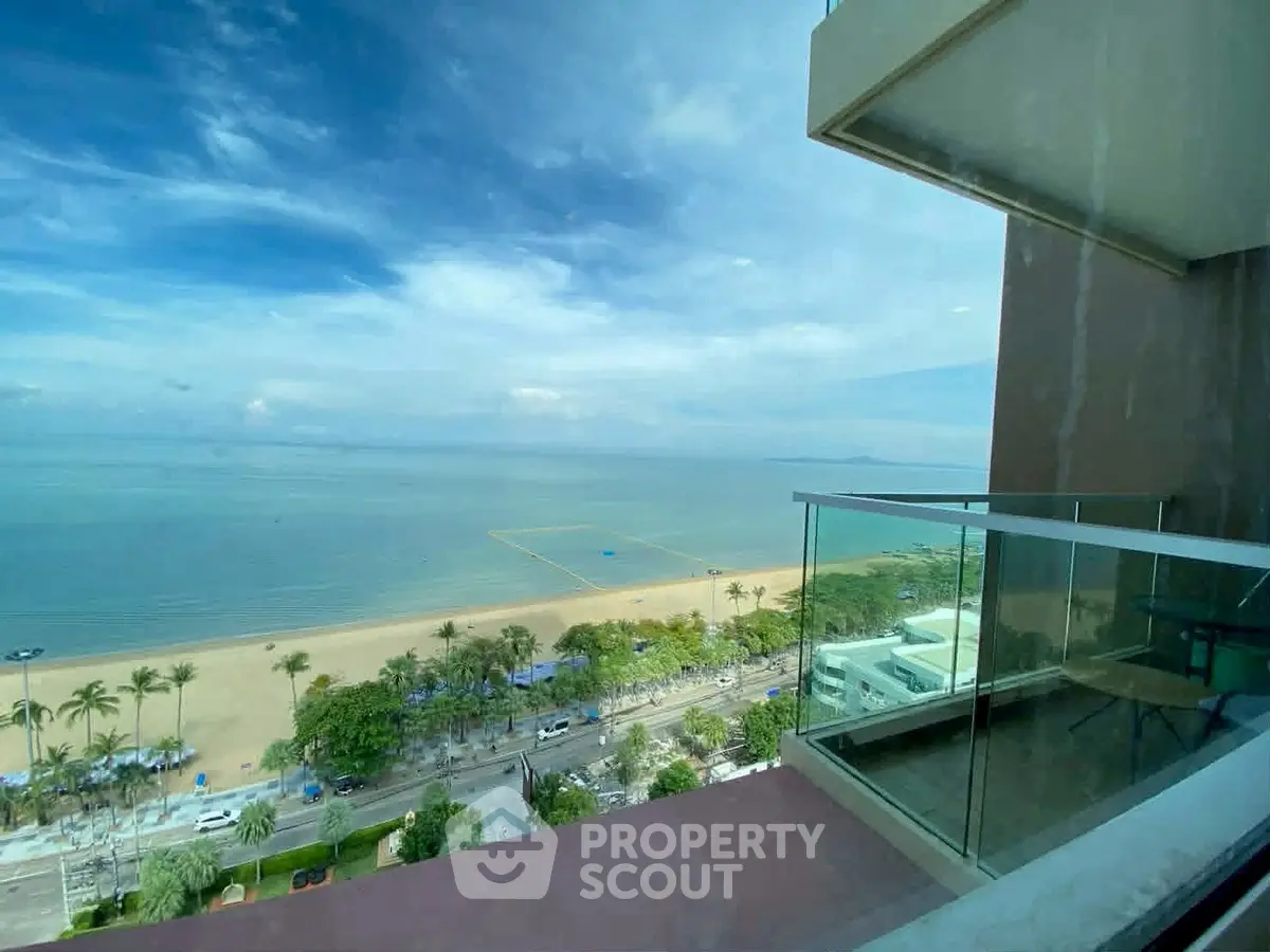 Stunning beachfront view from a modern balcony with glass railing, perfect for relaxation and enjoying the ocean breeze.