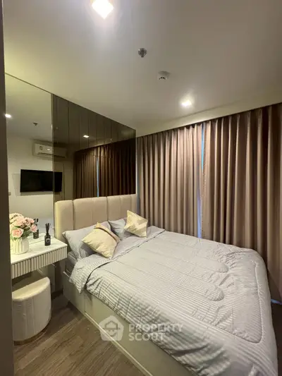 Cozy bedroom with modern decor and mirrored wall, featuring a comfortable bed and elegant curtains.