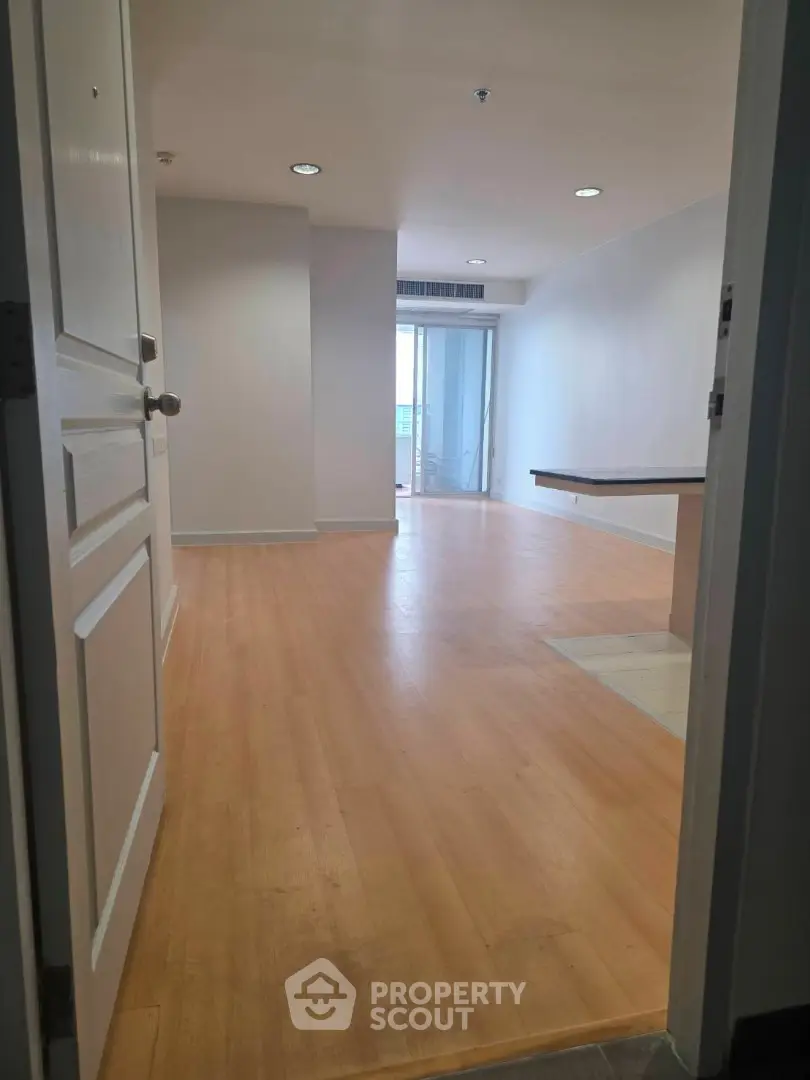 Spacious open-plan living area with wooden flooring and natural light, ideal for modern living.
