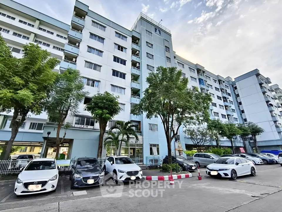 Modern apartment building with parking and lush greenery, ideal urban living environment.