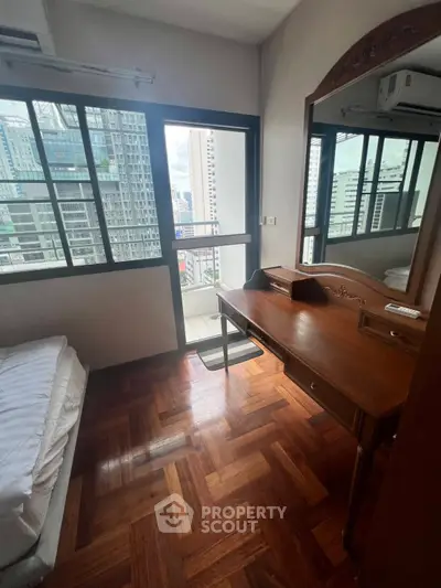 Cozy bedroom with wooden flooring and city view balcony access in modern apartment