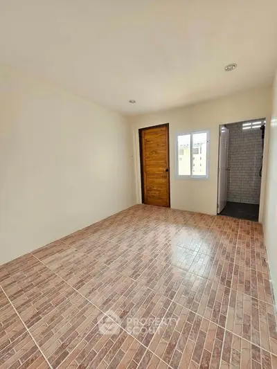 Spacious empty room with tiled flooring and wooden door, ready for customization.