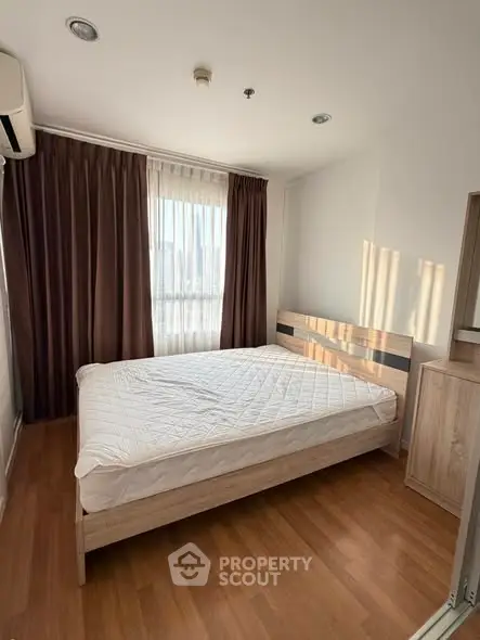 Cozy bedroom with wooden flooring and large window for natural light