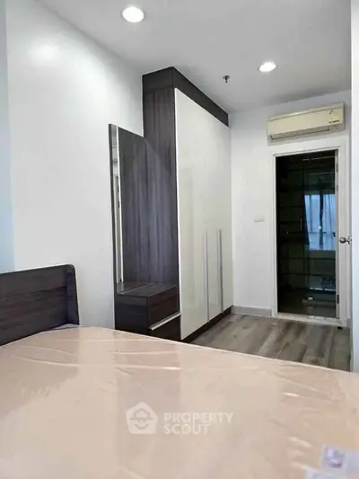 Modern bedroom with sleek wardrobe and air conditioning in a stylish apartment.