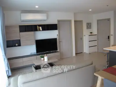 Modern living room with sleek furniture and neutral tones, featuring a wall-mounted TV and air conditioning.