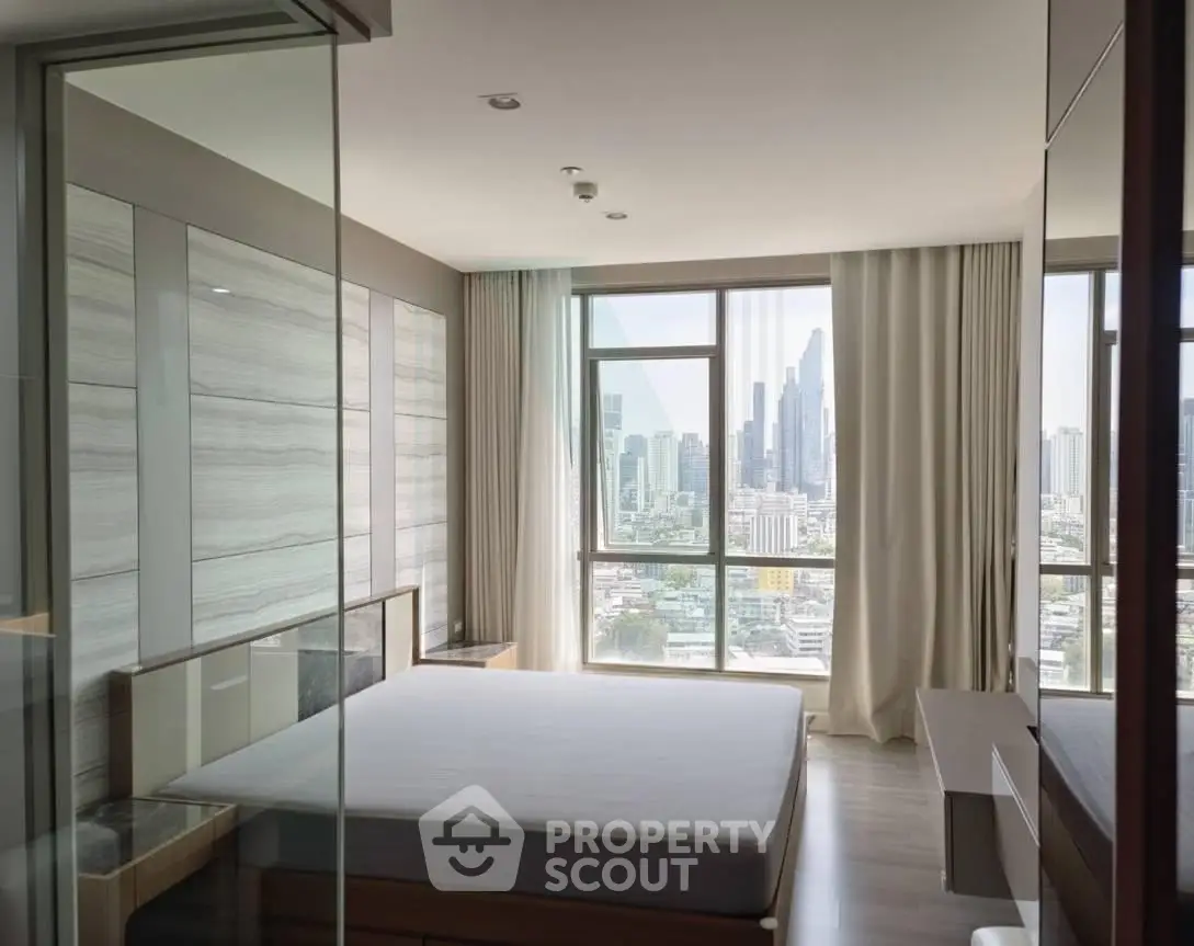 Modern bedroom with city view, large windows, and sleek furnishings in a high-rise apartment.