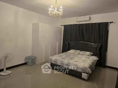 Spacious bedroom with elegant chandelier and modern decor