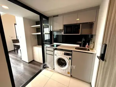 Modern compact kitchen with washing machine and sleek cabinetry in a stylish apartment.