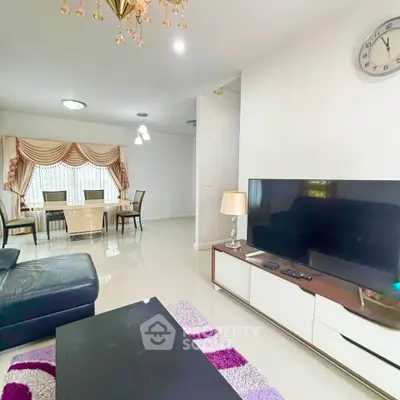 Spacious living room with modern decor and dining area, featuring elegant lighting and a sleek TV setup.