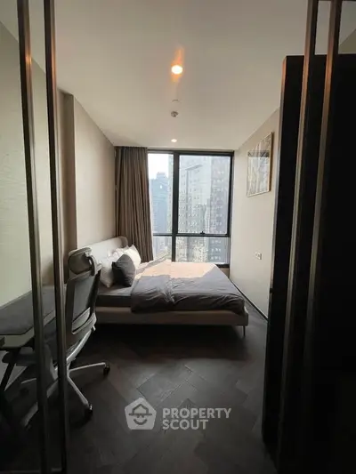 Modern bedroom with city view, featuring sleek furniture and large windows in a high-rise apartment.