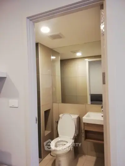 Modern bathroom with sleek design and compact layout, featuring a toilet and sink.