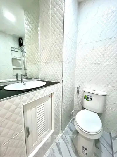 Modern bathroom with sleek white tiles and contemporary fixtures.