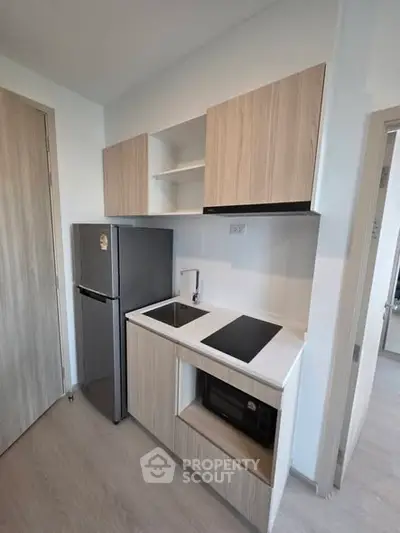 Modern compact kitchen with sleek cabinetry and built-in appliances in a stylish apartment.