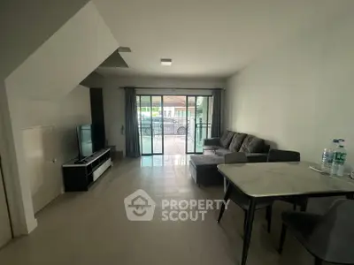 Spacious living room with modern furniture and large glass doors leading to a patio.