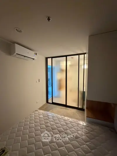 Modern bedroom with frosted glass partition and air conditioning unit.