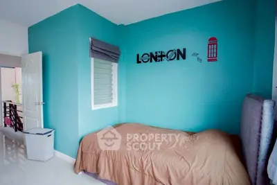 Cozy bedroom with teal accent wall and modern decor, perfect for a relaxing retreat.