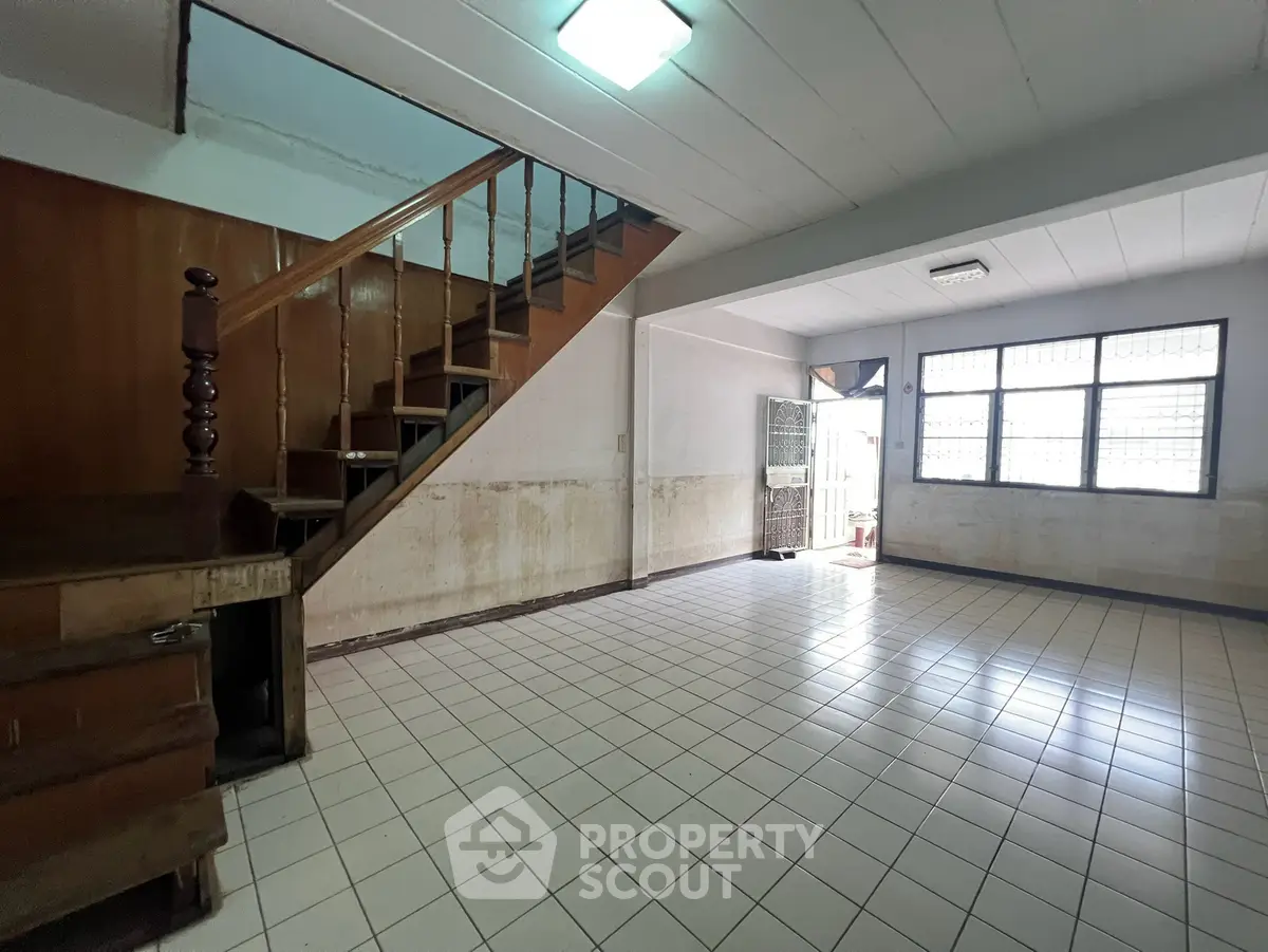 Spacious open-plan living area with staircase and tiled flooring, perfect for customization.