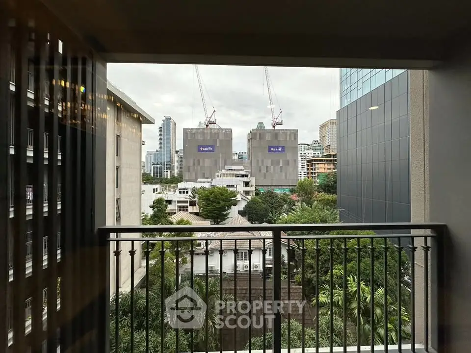 Stunning urban view from a balcony overlooking cityscape and construction cranes.