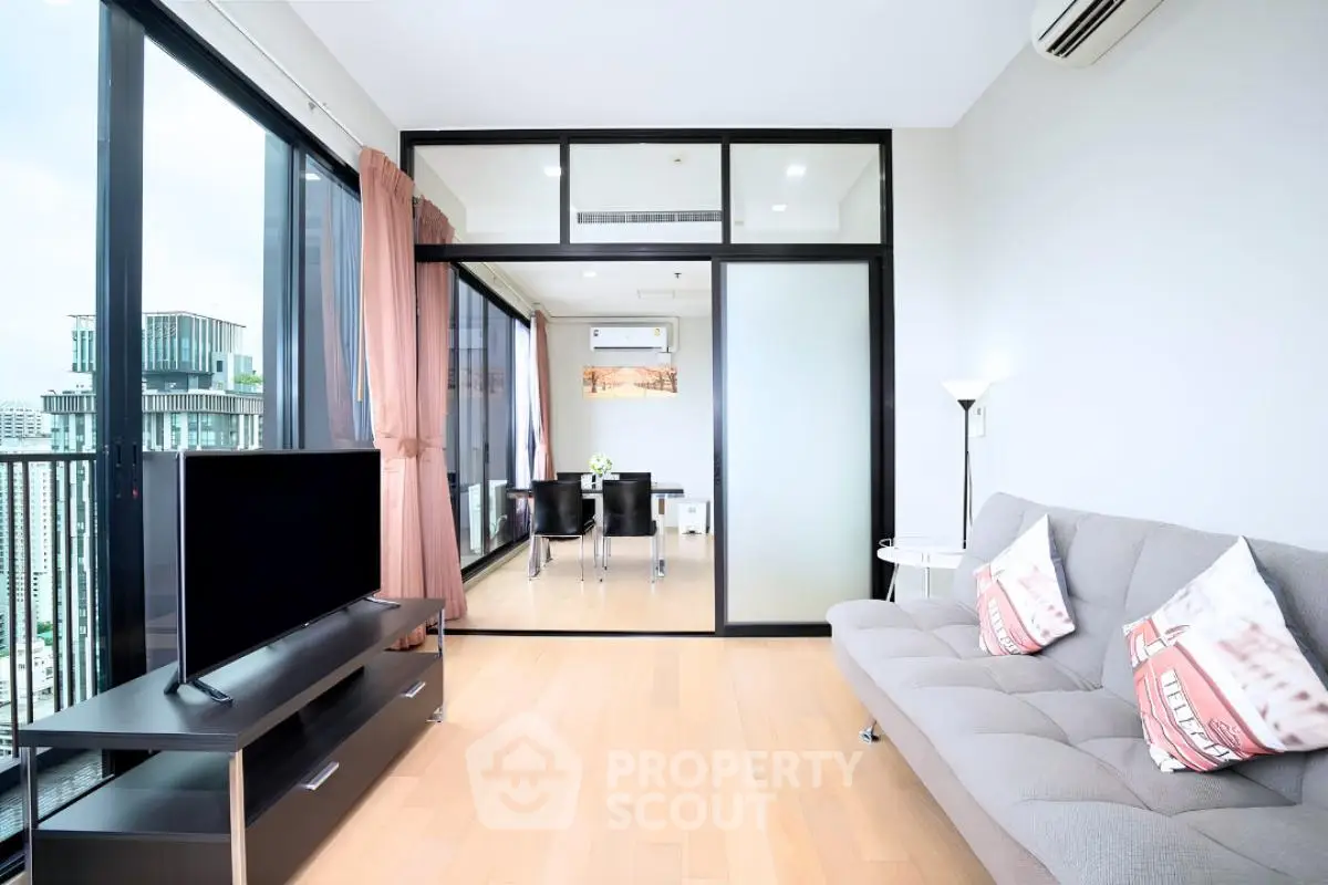 Modern living room with city view, featuring sleek furniture and large windows for natural light.