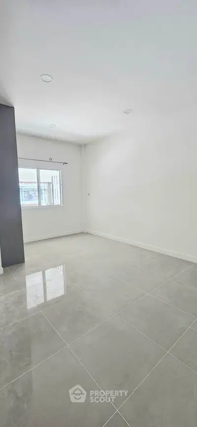 Spacious empty room with large window and glossy tiled floor, perfect for customization.