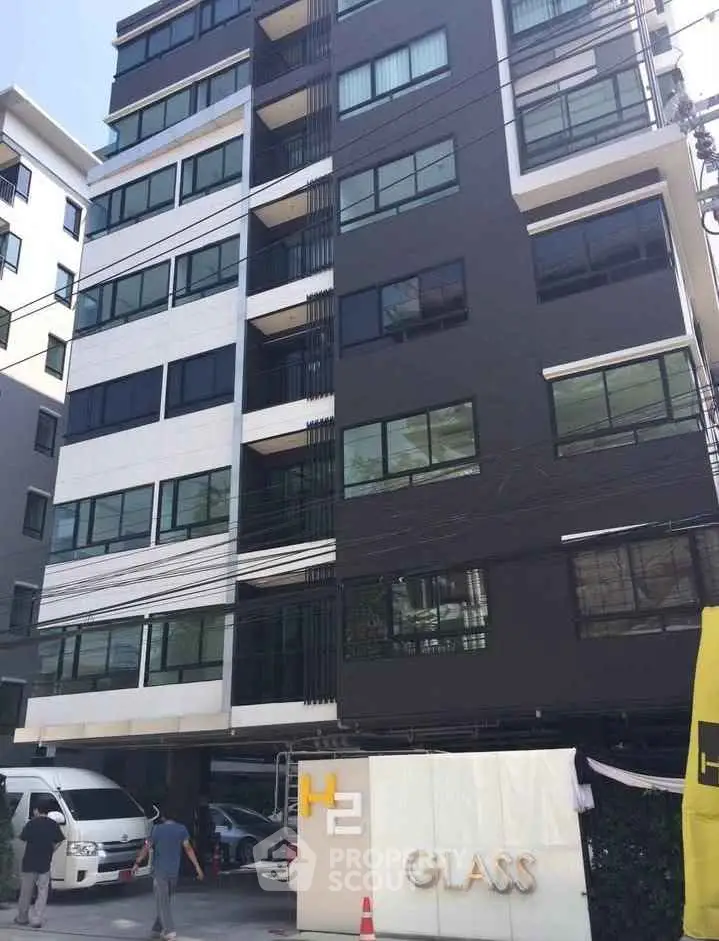 Modern urban apartment building with sleek design and large windows in a vibrant city setting.