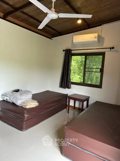 Cozy bedroom with twin beds, air conditioning, and a serene garden view, perfect for relaxation.