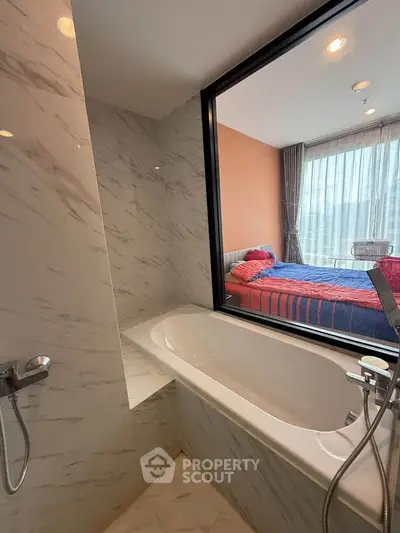 Modern bathroom with bathtub and window view into bedroom