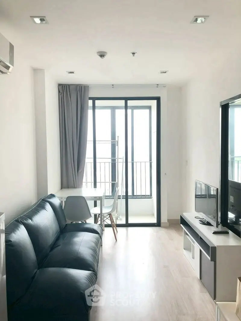 Modern living room with sleek black sofa and balcony view