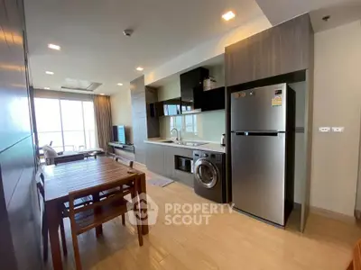 Modern open-plan kitchen and living area with sleek appliances and wooden dining set.