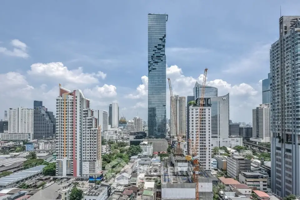 Stunning cityscape view with modern skyscrapers and construction cranes under a clear blue sky.