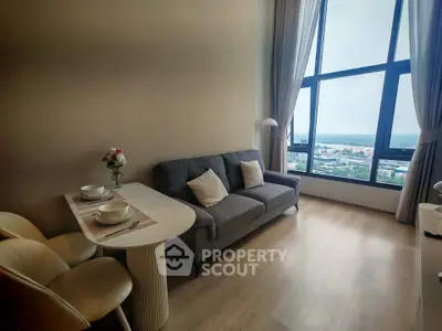 Modern living room with large windows offering stunning city views, cozy sofa, and elegant dining area.