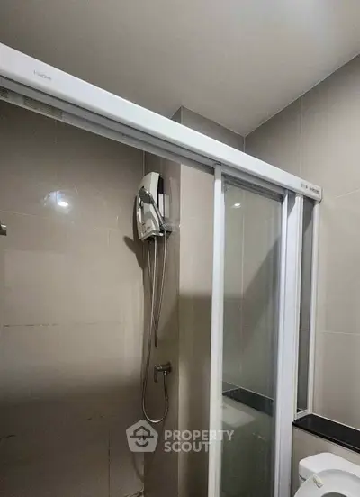 Modern bathroom with sleek shower and glass door in contemporary apartment.