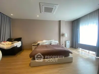 Spacious bedroom with modern decor and large windows for natural light.