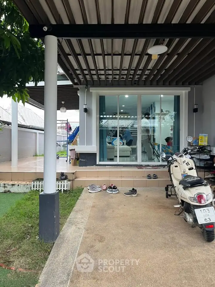 Modern home exterior with covered parking and glass sliding doors leading to a cozy living room.