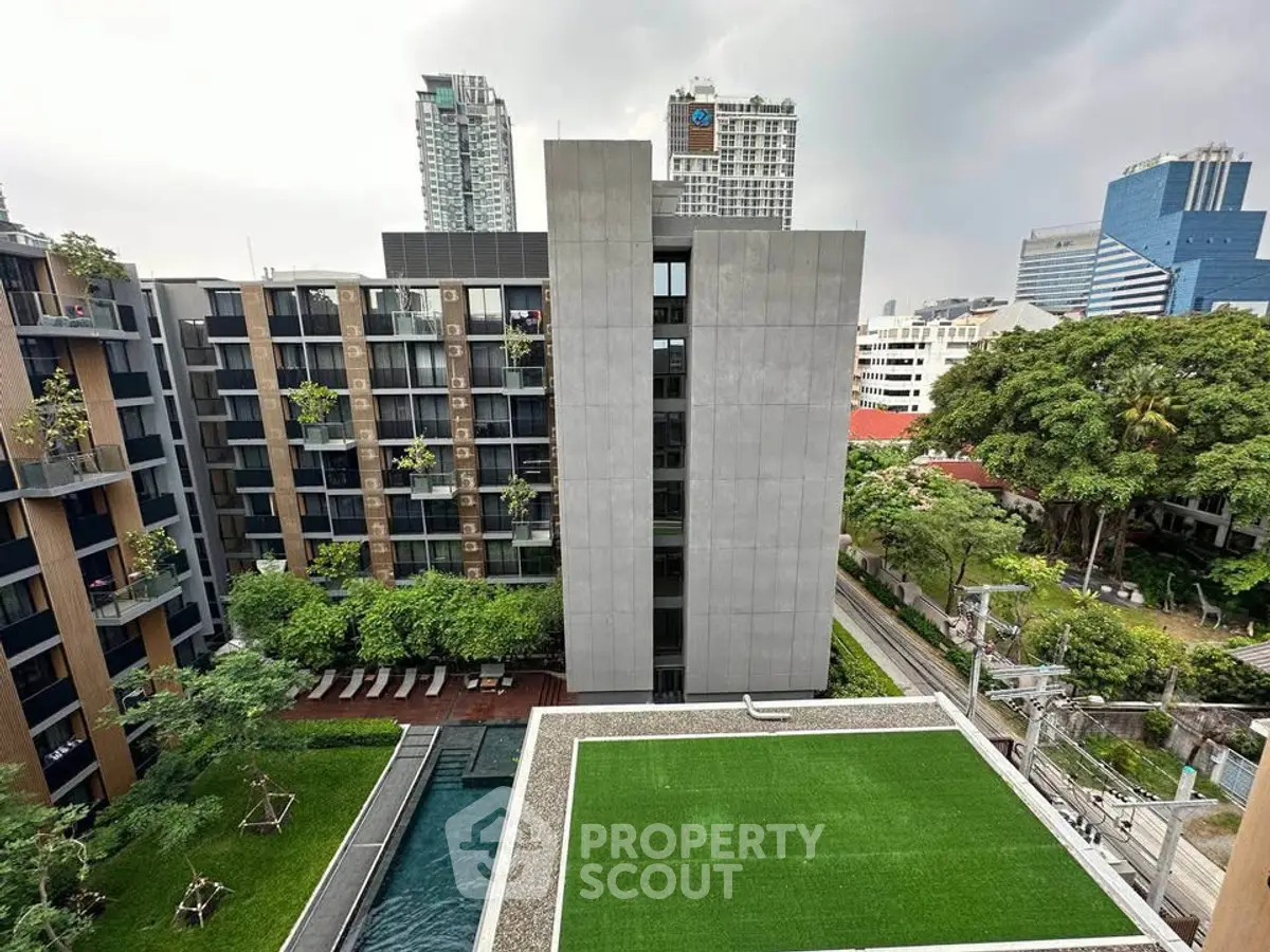 Modern urban apartment complex with pool and green rooftop garden.