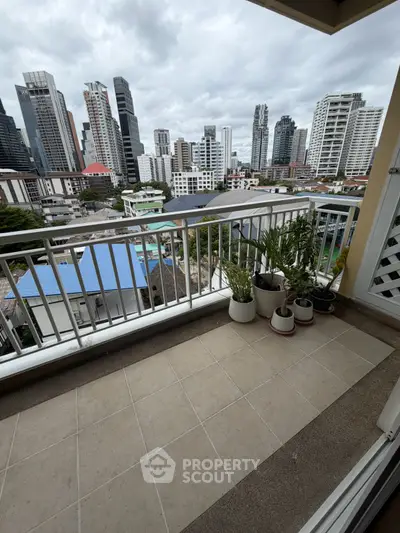 Spacious balcony with city skyline view and potted plants, perfect for urban living.