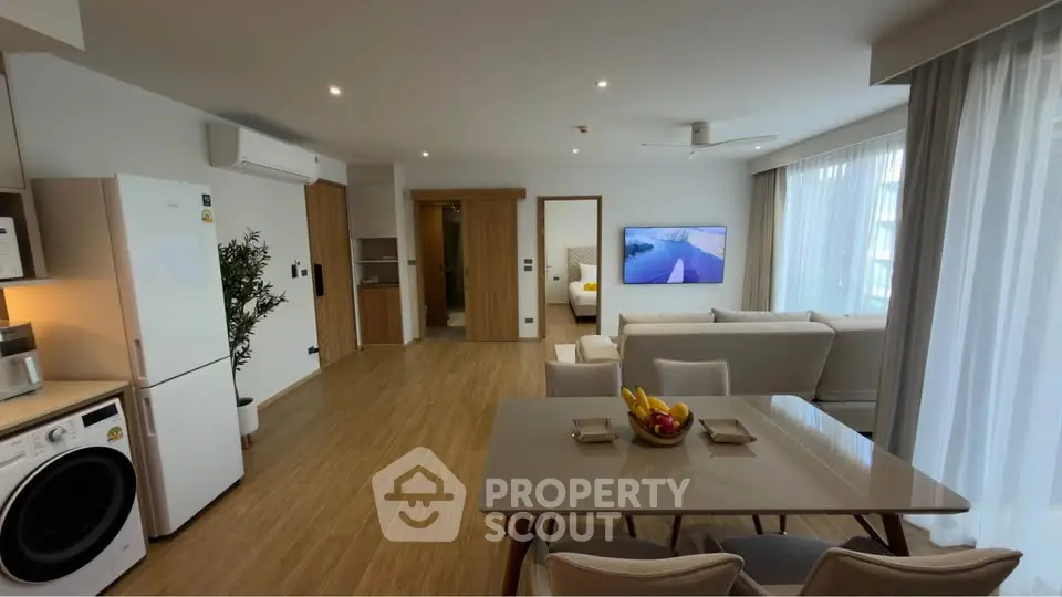 Modern open-plan living room with kitchen, featuring sleek appliances and cozy seating area.