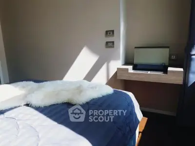 Cozy bedroom with modern decor and natural light, featuring a stylish bed and sleek side table.