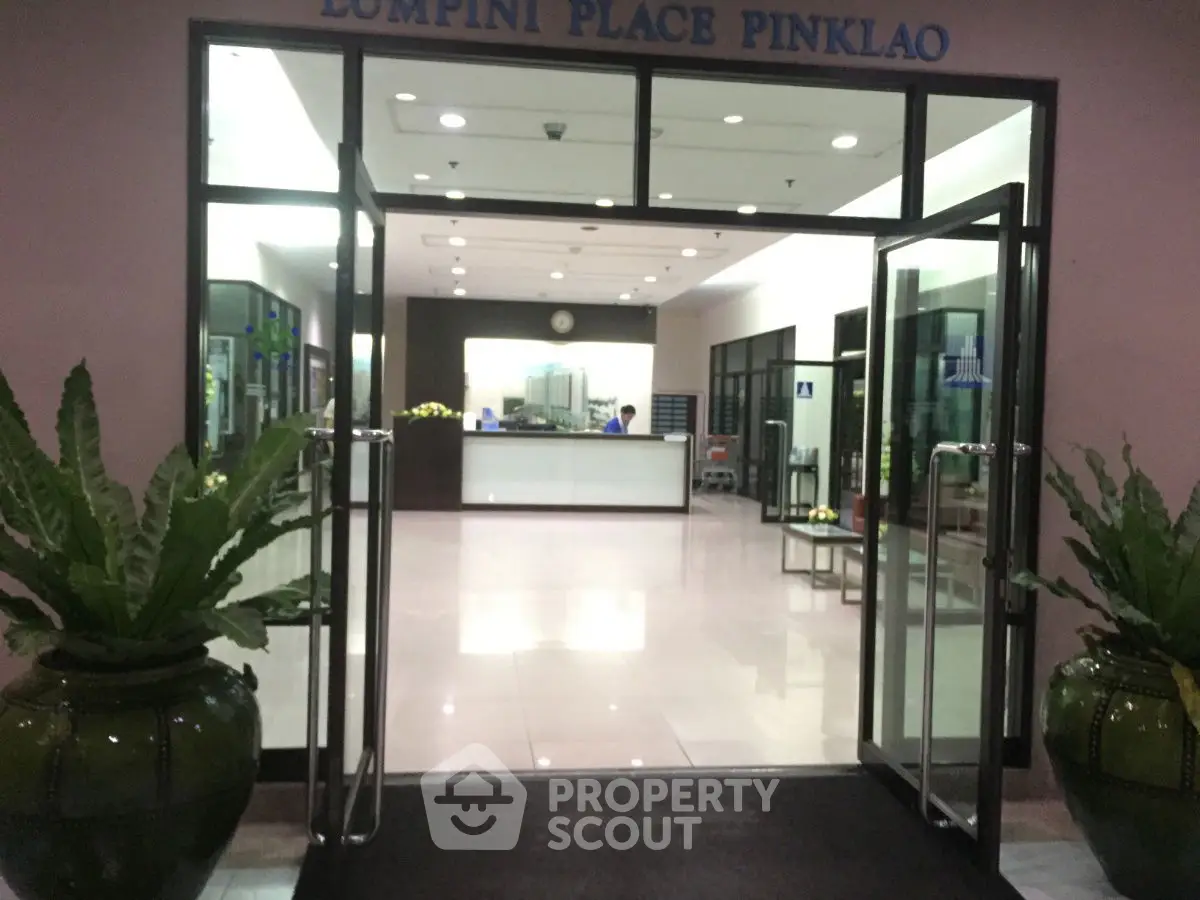 Elegant entrance of Lumpini Place Pinklao with glass doors and potted plants.