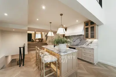 Luxurious open-layout kitchen with marble countertops and elegant lighting in modern home.
