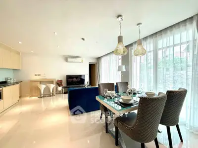 Spacious modern living room with open kitchen and elegant dining area, featuring large windows and stylish decor.