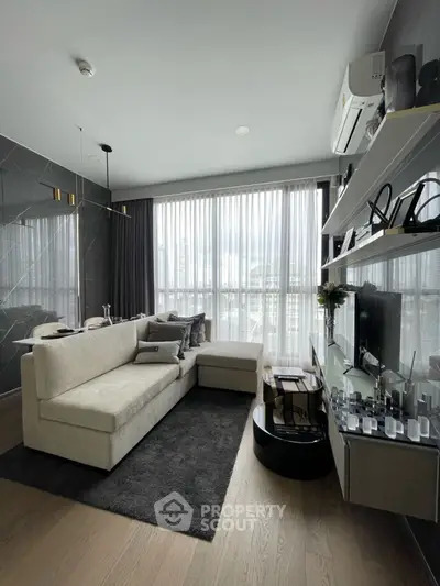 Modern living room with large windows and stylish decor in a high-rise apartment.